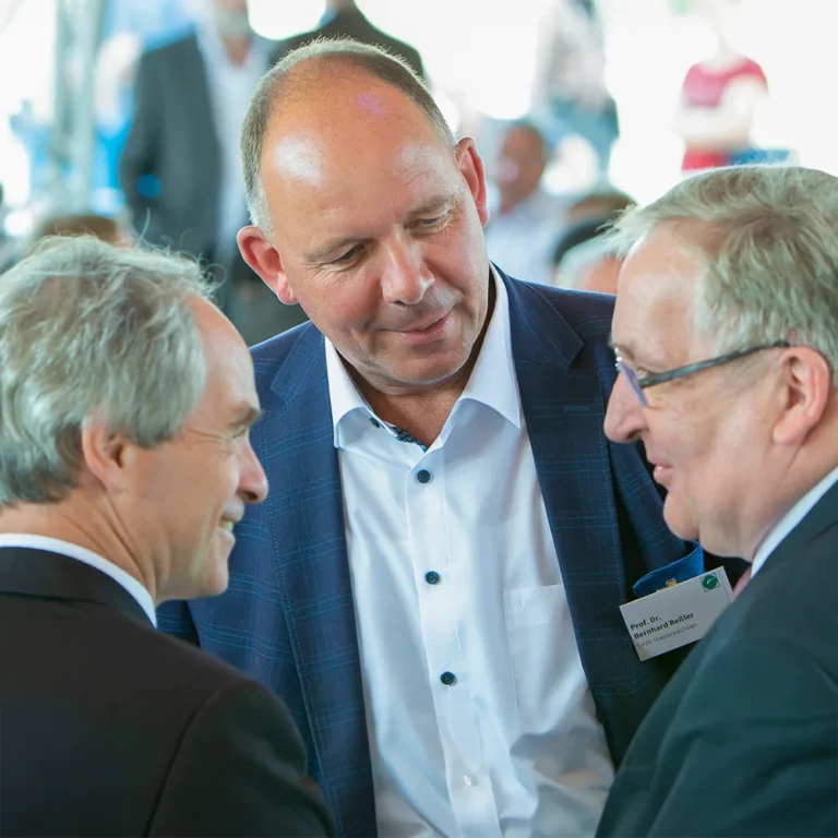 Eventfoto Geschäftliches Treffen - Drei Männer in Anzügen unterhalten sich angeregt bei einem Networking-Event.